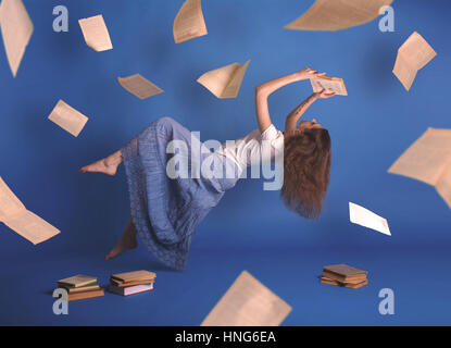 Surreal creative design, levitation. Flying woman. Levity people. Reading girl. Pages of books flying in the air. Floating in the air magic book. Stock Photo