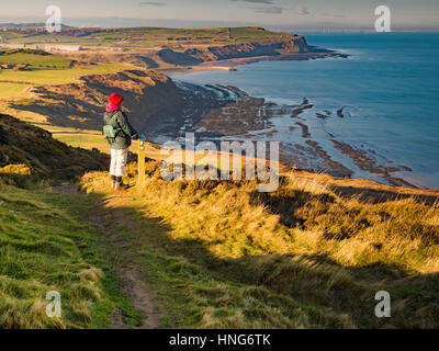 Elderly Female walker on the Cleveland Way taking in the view over Tees Bay from above Hummersea Scars Stock Photo