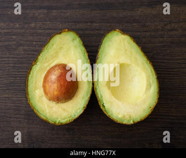 Two halves of a cut avocado on a wood surface Stock Photo
