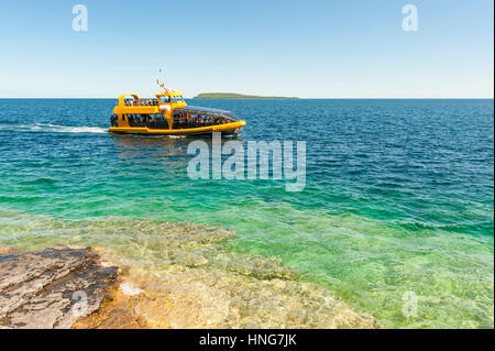 A tour boat passes by the shore of Flowerpot Island on Georgian Bay at Fathom Five National Marine Park, Bruce Peninsula, Ontario, Canada. Stock Photo