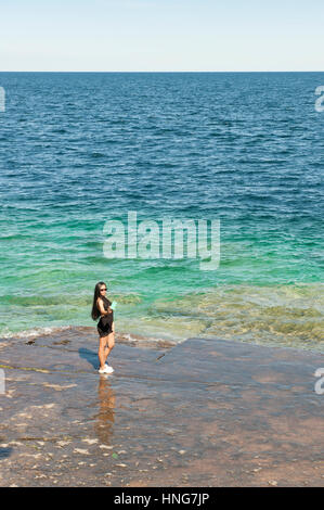Female asian tourist taking a selfie with a smartphone by the edge of Lake Huron, Georgian Bay, Bruce Peninsula, Ontario, Canada. Stock Photo