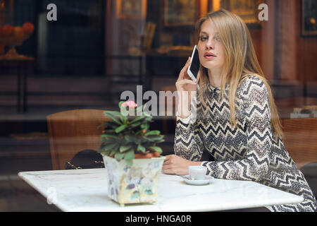 Beautiful woman calling with her smartphone. City cafe Stock Photo