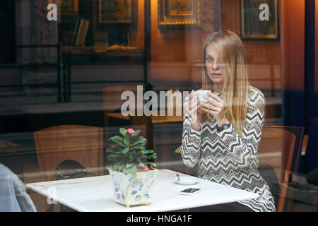 Woman with a cup of coffee. Urban shot through the window Stock Photo