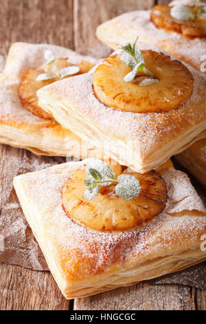 Puff pastry cake with pineapple, decorated with mint and powdered sugar close-up on the table. vertical Stock Photo