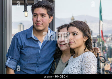 family portrait on rooftop dining terrace of Holiday Inn includes proud Mexican mother with handsome adult son & stylish pretty daughter Stock Photo
