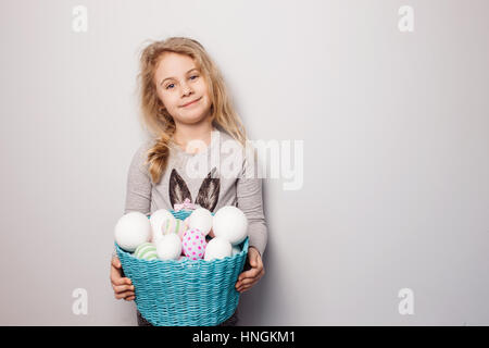 Little blonde girl holding basket with painted eggs. Easter day. Stock Photo