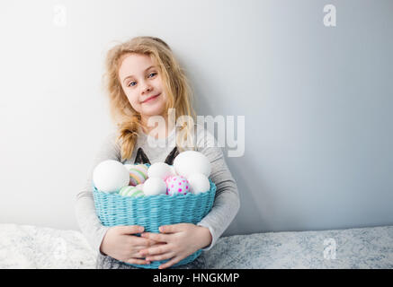 Little blonde girl holding basket with painted eggs. Easter day. Stock Photo
