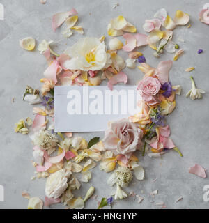 white envelope full of various flowers on a stone background . Flat lay. Love concept. Stock Photo