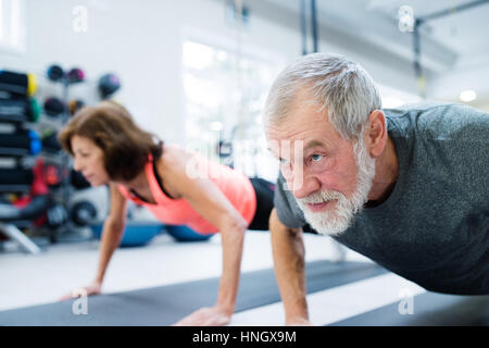 Senior couple in gym working out, doing push ups Stock Photo