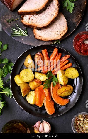 Roasted vegetables in frying pan and sliced barbecue meat, top view Stock Photo