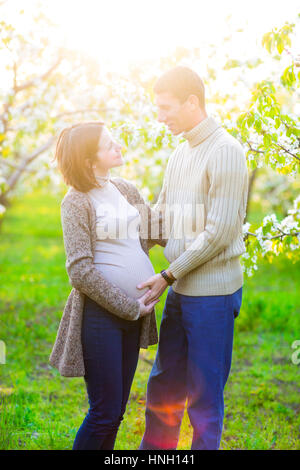 Portrait of a happy pregnant couple in the blossom garden Stock Photo