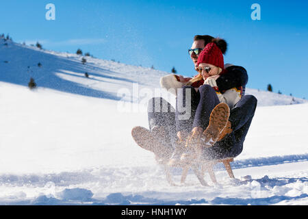 Young Couple Sledding And Enjoying On Sunny Winter Day Stock Photo