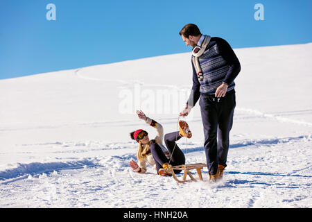 Man pulling girl on a sled at snow - concept: Winter fun Stock Photo