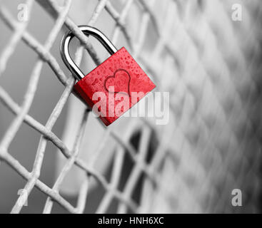 A red padlock with a heart symbol attached to a metal railing on a ...
