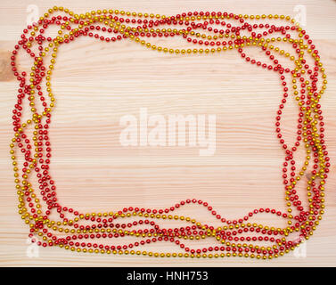 Red and gold beads on a wooden board New Year's beads. Christmas decorations. Garland. Frame of beads. Stock Photo