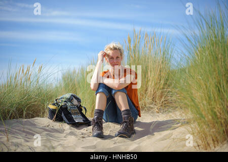 A woman sits thoughtfully in sand dunes Stock Photo
