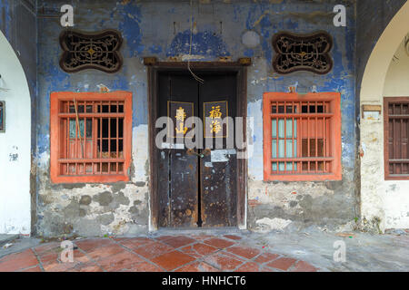 Old Run-Down Peranakan style home exterior with Chinese text Longevity Mountain and Properous Sea on wooden doors entrance Stock Photo