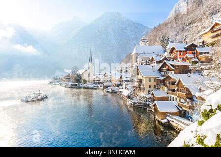 Classic postcard view of famous Hallstatt lakeside town in the Alps with passenger ship on a beautiful sunny day with blue sky and clouds in winter Stock Photo