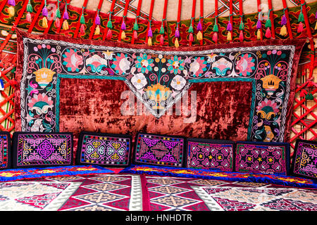 Traditional carpet, rug and pillow treatment details in the interior of a nomadic yurt Stock Photo
