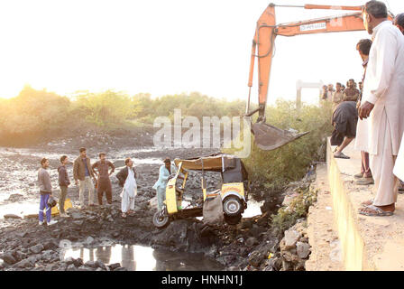 Crane picking up an auto rickshaw which strayed off into drain due to over speed, at Korangi Crossing Road in Karachi on Monday, February 13, 2017. Stock Photo