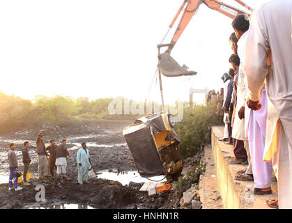 Crane picking up an auto rickshaw which strayed off into drain due to over speed, at Korangi Crossing Road in Karachi on Monday, February 13, 2017. Stock Photo