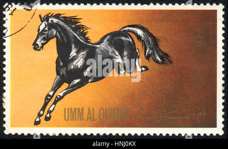 A postage stamp printed in Umm al-Qiwain  shows a black horse from series: Horses, circa 1971 Stock Photo