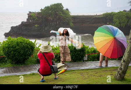 Tourists taking photos of each other near Tanah Lot Temple, Tabanan, West Bali. Batu Bolong Temple in background Stock Photo