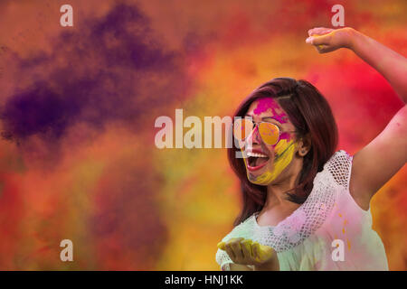 Portrait of a smiling girl with mirror sunglasses covered with colorful Gulal powder during a Holi festival Stock Photo