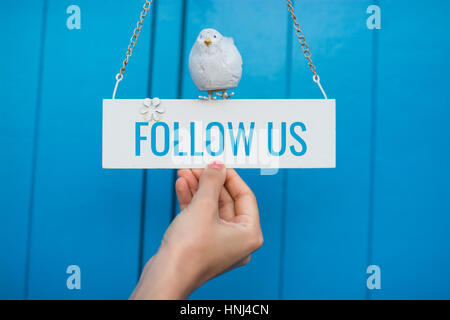Follow Us signboard on a blue wooden background Stock Photo