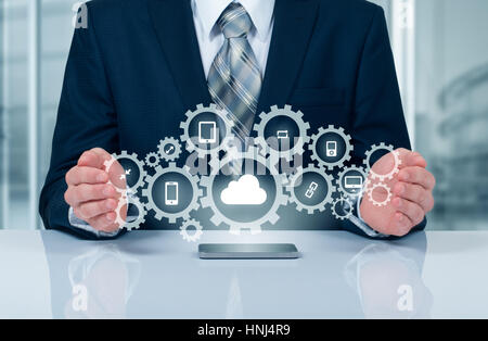 Businessman holding a cloud connected to many objects on a virtual screen concept about the internet of things. Stock Photo
