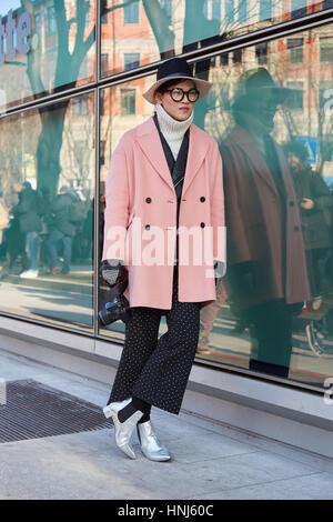 MILAN - JANUARY 14: Woman with pink coat and silver shoes before Emporio Armani fashion show, Milan Fashion Week street style on January 14, 2017 in M Stock Photo