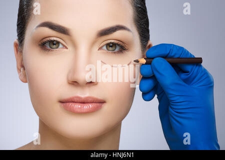 Surgeon drawing dashed line under eye Stock Photo