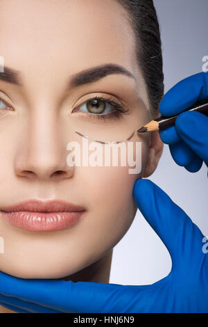 Surgeon drawing line under eye Stock Photo