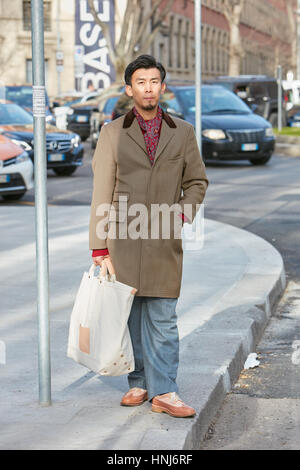 Elegant man with brown coat and red scarf before Emporio Armani fashion show, Milan Fashion Week street style on January 14, 2017 Stock Photo