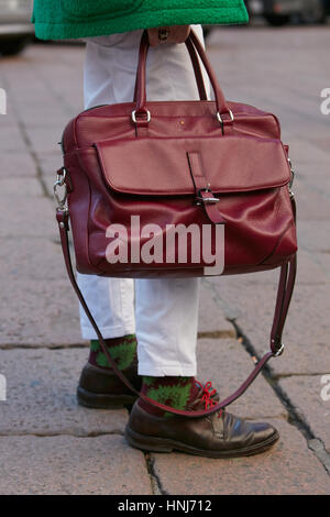 Man with dark red leather bag and white trousers before Salvatore Ferragamo fashion show, Milan Fashion Week street style on January Stock Photo