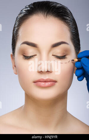 Doctor drawing dashed line under eye Stock Photo