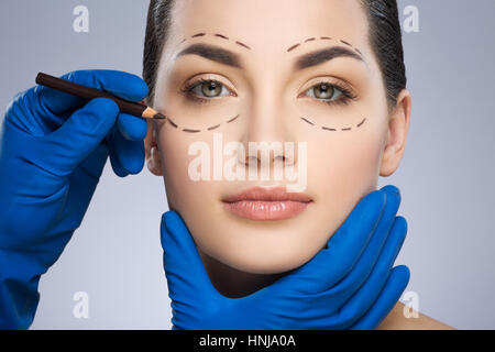 Plastic surgeon drawing dashed lines under eye Stock Photo