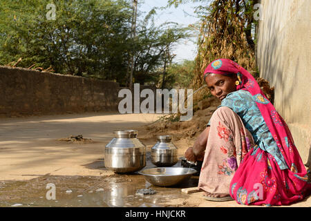 BHUJ, RAN OF KUCH, INDIA - JANUARY 13: The tribal woman in the village on the desert in the Gujarat state he is washing dishes by the route, Bhuj in J Stock Photo