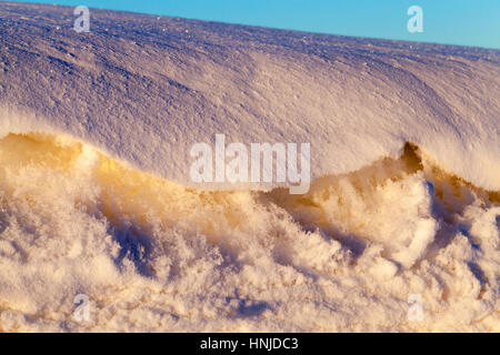 close-up photo was taken in winter time at sunset with a small depth of field. The surface of the snow on the field. On snow visible bumps and holes.  Stock Photo
