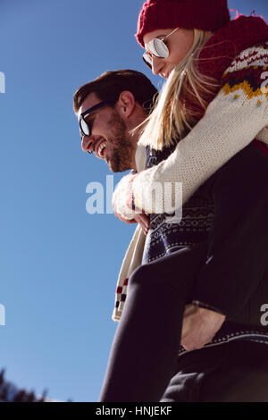 Couple playing in snow. Man giving woman piggyback ride on winter vacation. Stock Photo