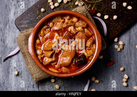 high-angle shot of an earthenware bowl with spanish callos, a typical beef tripe stew with chickpeas, morcilla and chorizo, on a rustic wooden table Stock Photo