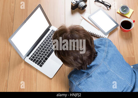 woman lying on floor using computer notebook with tablet and coffee cup Stock Photo