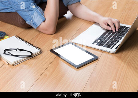 woman lying on wooden floor with computer notebook and tablet Stock Photo