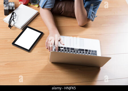 woman lying on wooden floor with computer notebook and tablet Stock Photo