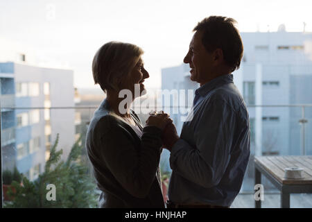 Silhouette of senior couple standing on balcony, holding hands Stock Photo