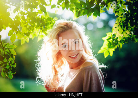 happy young woman illuminated by the setting sun in the park Stock Photo