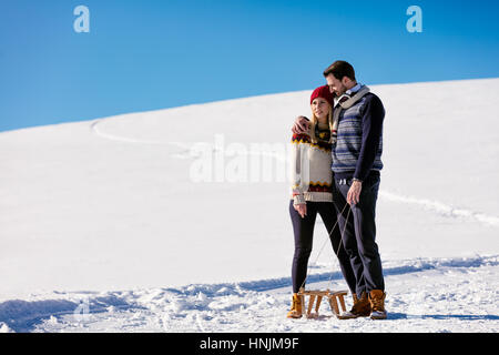 Man pulling girl on a sled at snow - concept: Winter fun Stock Photo