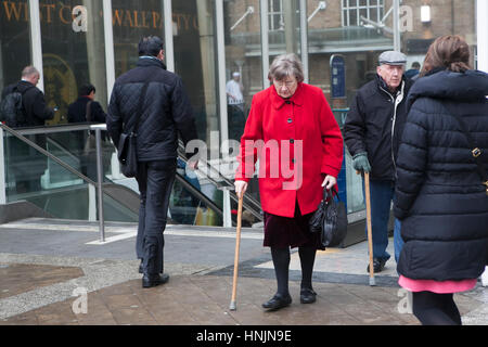 LONDON, UK - APRIL 22, 2016: An elderly woman in a red coat with a cane came out of the exit at Liverpool Station Stock Photo