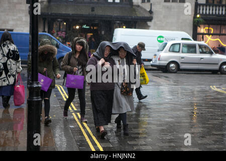 LONDON, UK - APRIL 22, 2016: Tourists covered their head by blanket , walk on the street in the rain Stock Photo