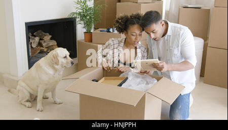 Golden retriever watching his owners pack up their belongings in cardboard boxes to move house Stock Photo